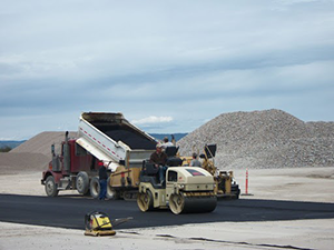 Delivery of asphalt and roller machine compacting and smoothing the material.