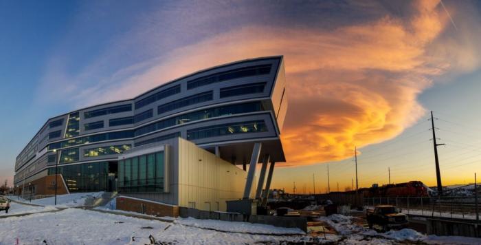 Denver Water's new Administration Building, all the angles lit up against the billowing, orange-colored cloud at sunset.