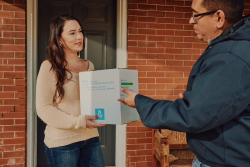 A woman receives a box with a water pitcher and filter from a Denver Water employee.