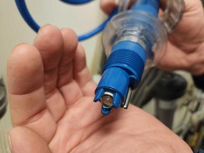 Hands hold a blue plastic and clear glass sensor, with fingers cupping around the device.