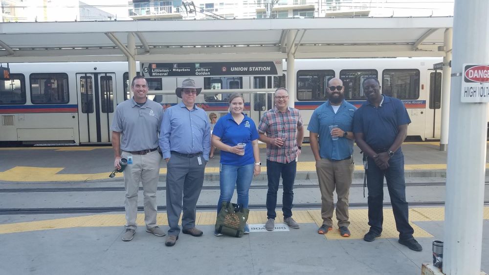 Group of people stand near light rail train