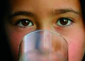 Child drinking water, camera focused on child's eyes.