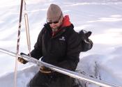 Denver Water employee holding long metal snow measuring device.