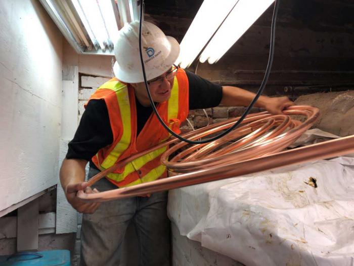 Denver Water Crew member holding copper pipe in customers basement.