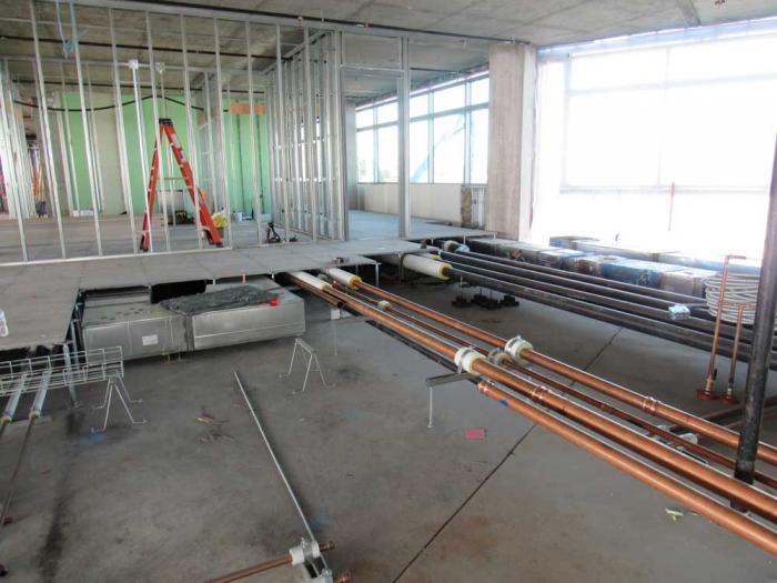 Copper pipe runs through the floor of a building under construction. 