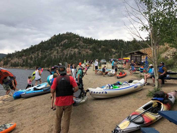People crowded around a boat ramp with paddleboards and kayaks.