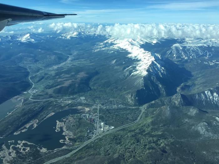 A mountain range seen from the air, with a piece of a plane's wing in the upper edge of the picture.