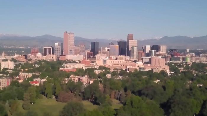 Downtown Denver is seen against blue skies and the mountains. 