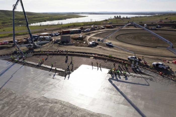 A view from a done flying over the round base of the storage tank, while concrete is poured on it.