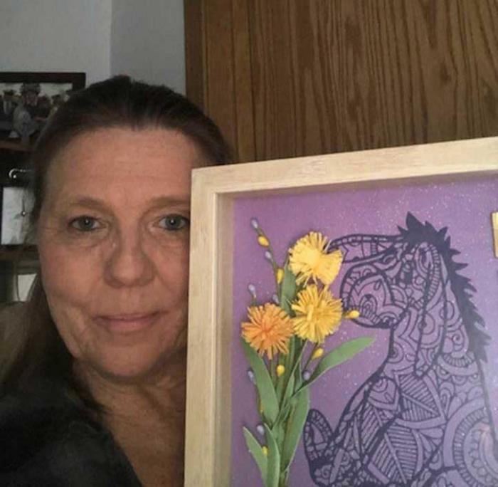 A woman holds a framed picture of Eeyore.