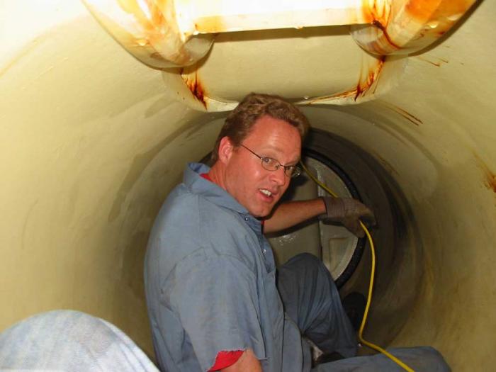 A man inside a small tunnel turns to look at the camera.