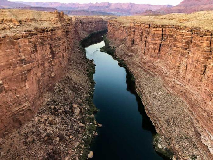 A blue ribbon of river runs between the red cliffs of a canyon.