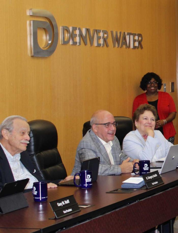 Three people sitting at a conference table, under Denver Water's logo on the wall.