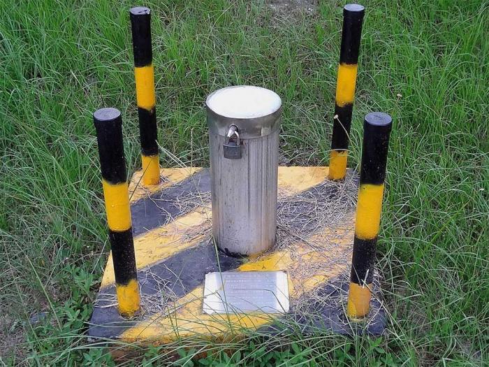 Monitoring wellhead which consists of 4 protruding beam in the corners and a metallic cylinder in the middle. 