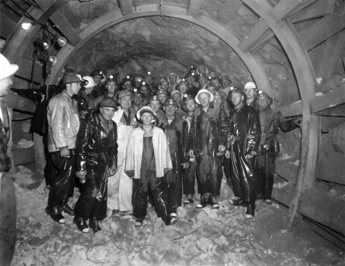 Historical black and white photo of a group of men working in a tunnel.