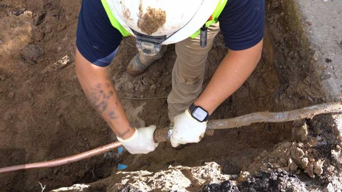 Worker connecting new copper pipe at a home.