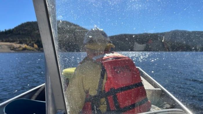 A firefighter rides a boat to fire at Gross Reservoir
