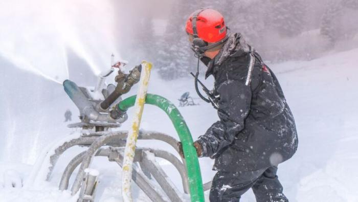 Man operates snowmaking machine