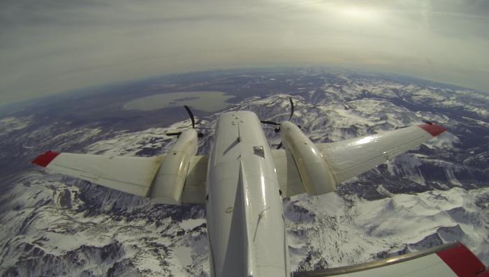 A plane flying over snowpacked mountains.