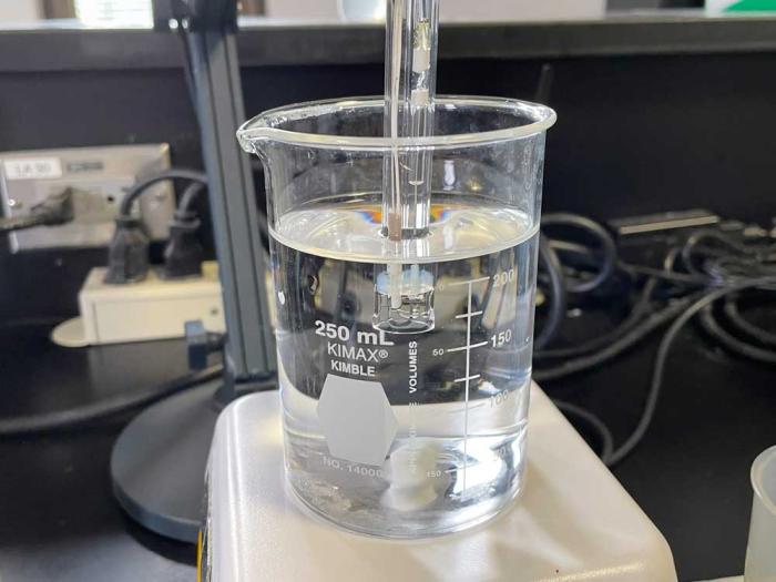 A glass beaker of water with a testing instrument in it. 
