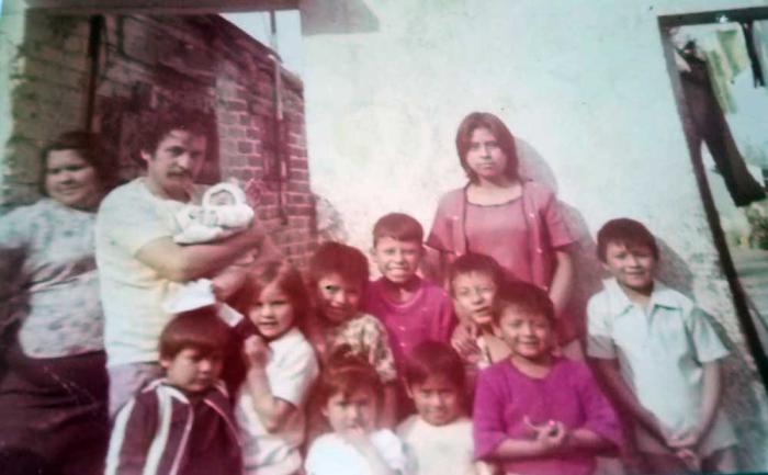 Old picture of several children and a woman smiling for the camera.
