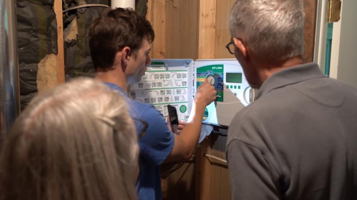 People looking at the control panel of an irrigation sprinkler system.