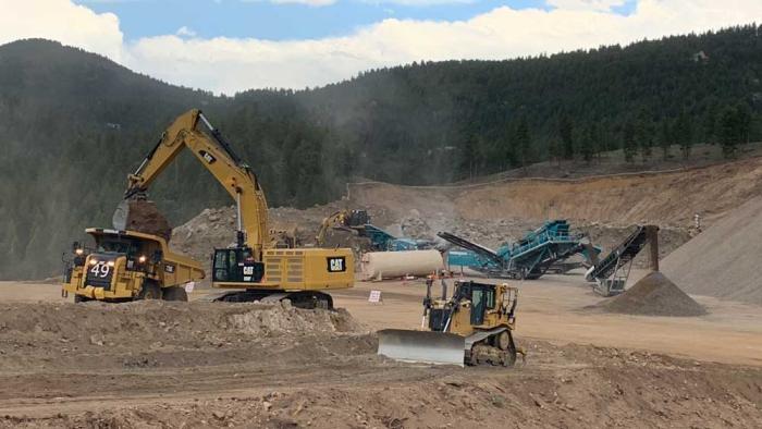 More equipment in the dirt, with trees on the hillside above.