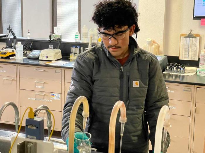 A man in safety goggles tests water with a probe
