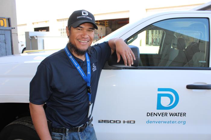 Denver Water employee stands in front of vehicle displaying Denver Water logo
