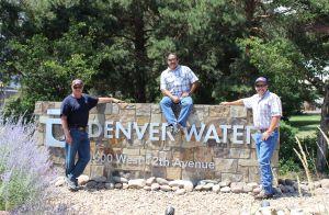 Employees stand near Denver Water sign