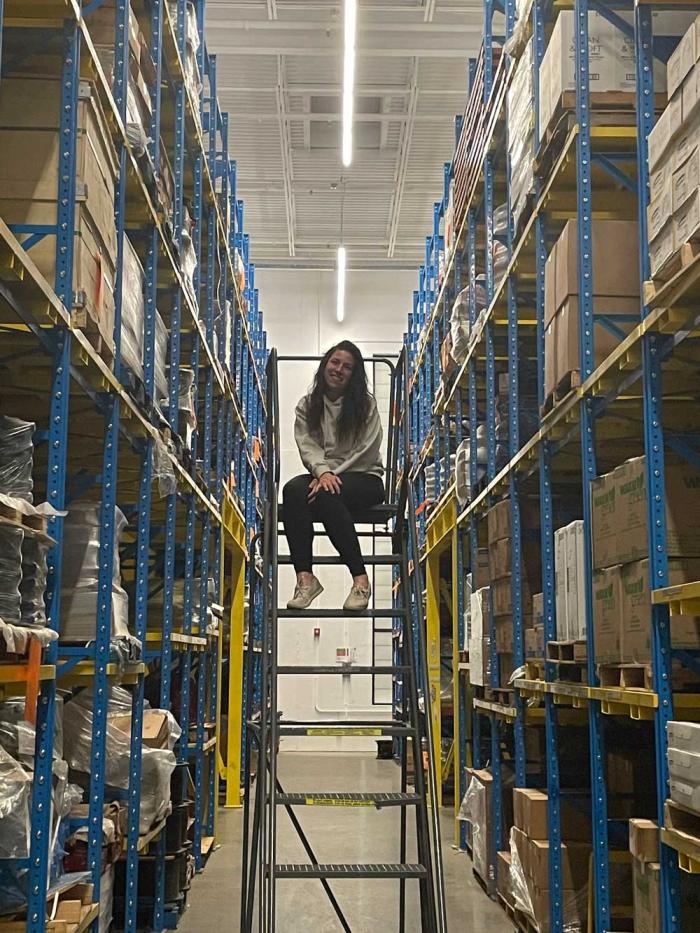 Woman sits on a ladder near shelves