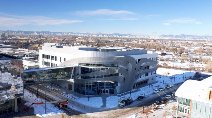 Curving exterior of a building with snow-capped mountains in the background.