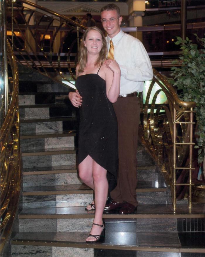 A man and a woman, dressed formally, stand on stairs. 