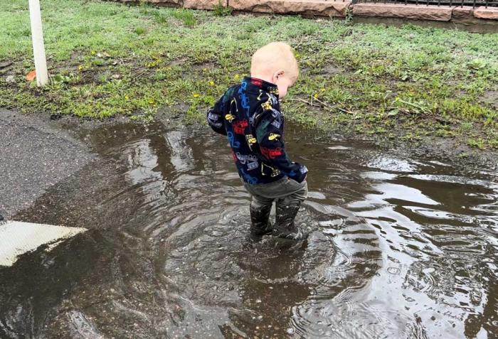 A child splashes in a rain puddle.