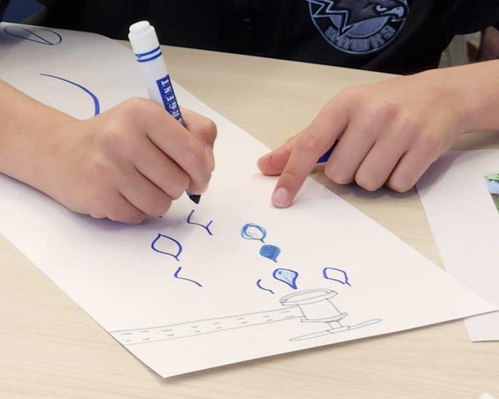 A child uses a marker to draw on a piece of paper.