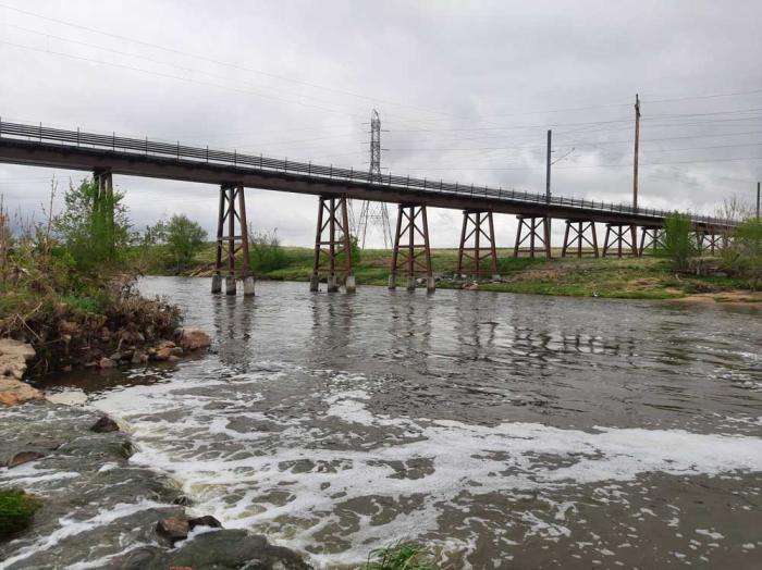 A river swollen from recent rains runs under a bridge.