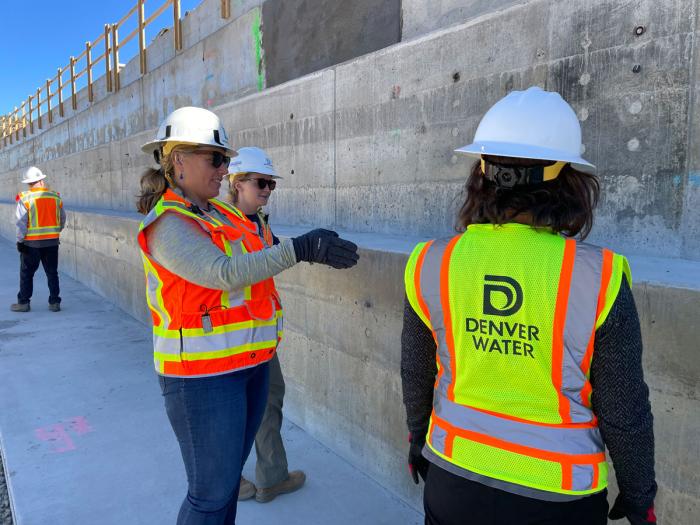 Women in Denver Water safety vets and helmets examine concrete steps. 