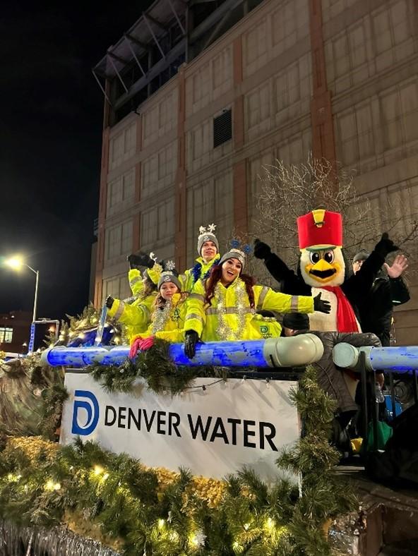 People stand on a float that says "Denver Water" they're waving at the crowd and happy to be a part of the celebration.