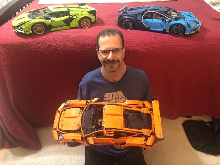 Man holds a Lego model of a yellow car
