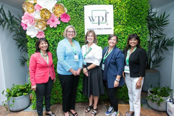 Five women stand in front of a green wall