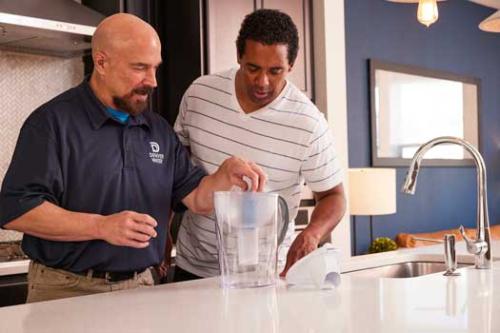 A Denver Water employee shows a male homeowner how to install a filter in a water pitcher.