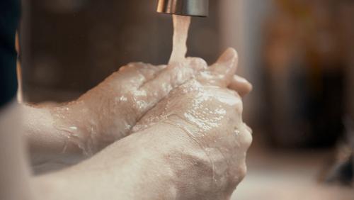 Hands underneath a faucet washing. 