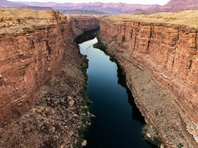 A ribbon of blue water runs between the cliffs of a deep, red-rock canyon.