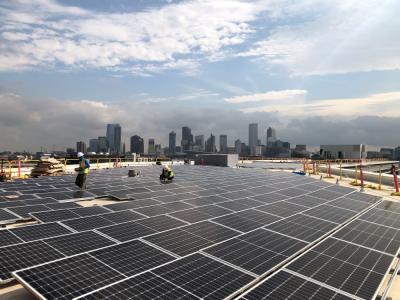 Crews install solar panels on building roof