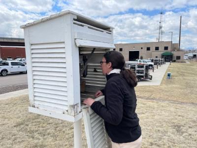 Woman looks inside a white box that houses a weather station