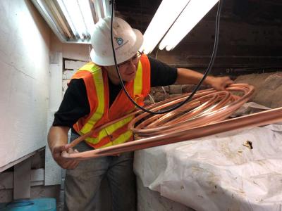 A man in a Denver Water hard had with a coil of copper pipe in a basement. 