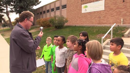 Matt Bond shows Green School students how to save water with showerhead.