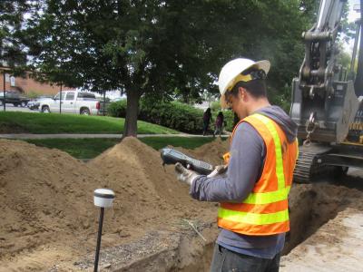 Worker uses a GPS computer to record the location of newly laid pipe.