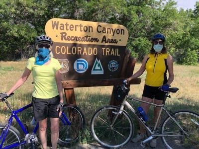 Two of the first recreationists pose by Waterton Canyon sign on reopening day, Monday, June 15, 2020.