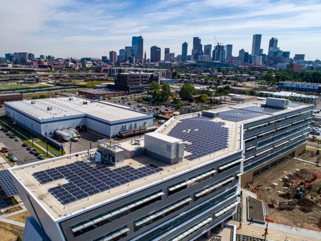 Solar power panels on a roof, with downtown Denver in the background.